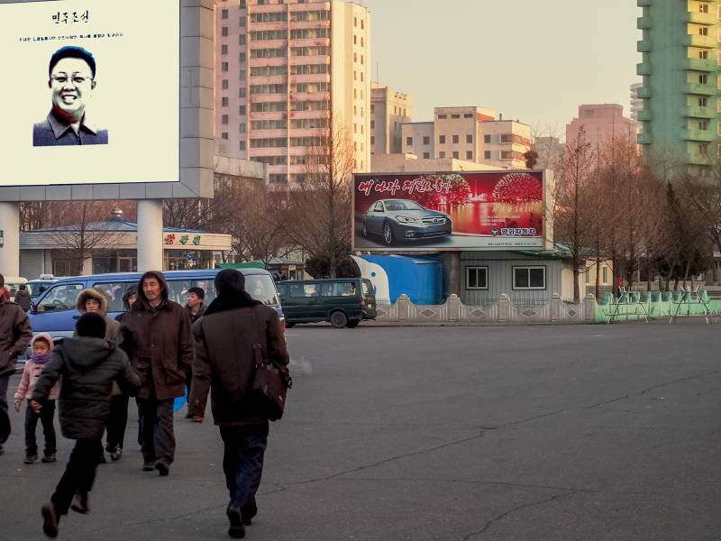 2016, Pjöngjang, Leuchtreklame mit Kim Jong-Il und eine Werbung für den Auto-Eigenbau «Pyeonghwa».